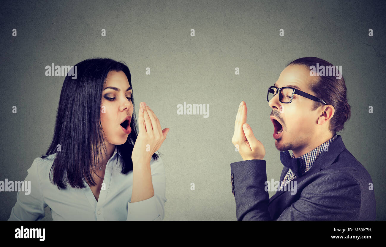 Young couple woman and man checking their breath with hand gesture Stock Photo