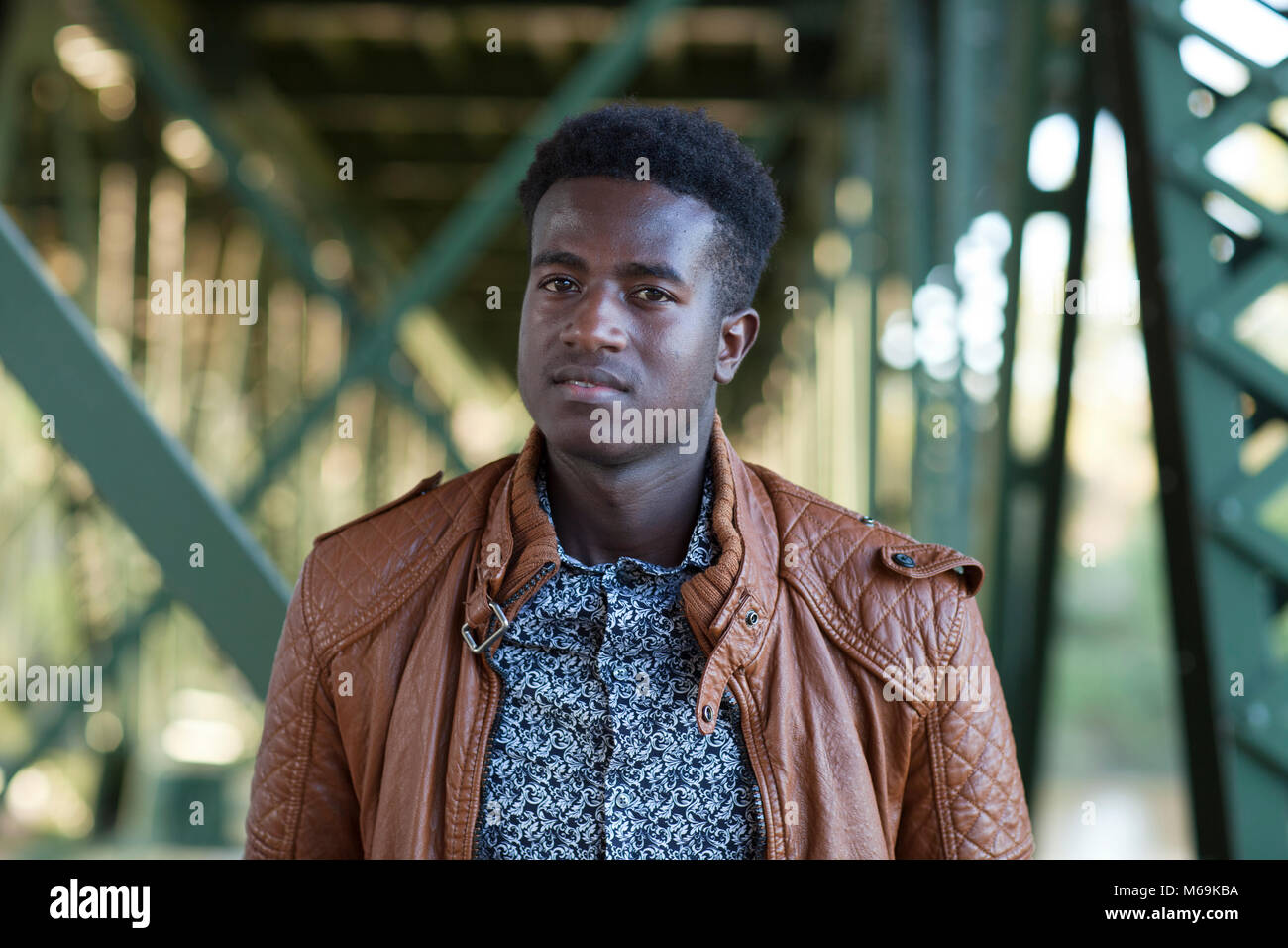 Selective focus image of a handsome young black man standing below girders of a bridge Stock Photo