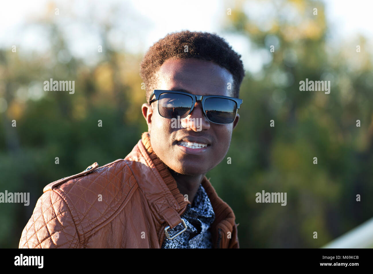 A handsome young black man in sunglasses and a leather jacket on a fall day Stock Photo