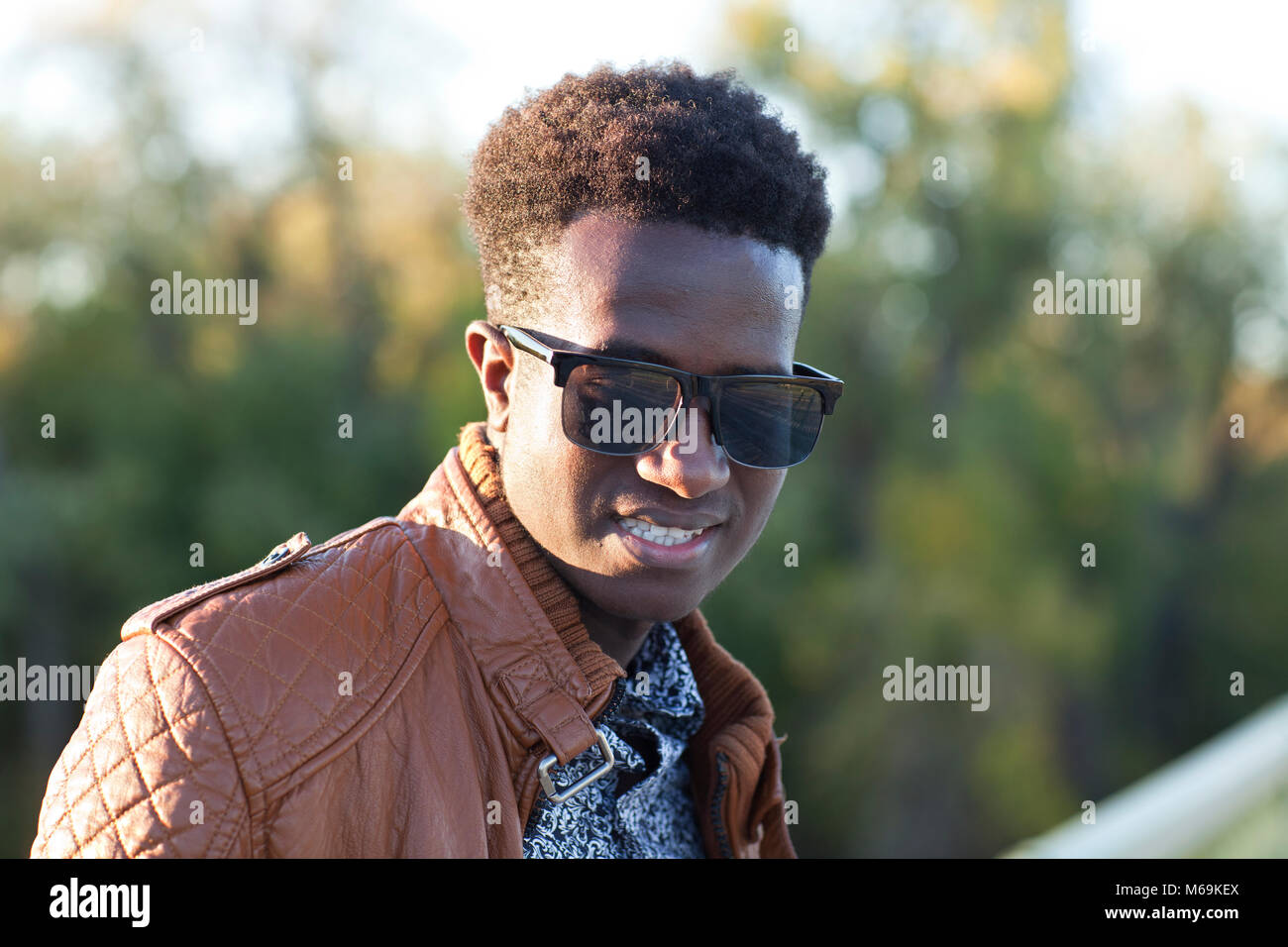 A handsome young black man in sunglasses and a leather jacket on a fall day Stock Photo