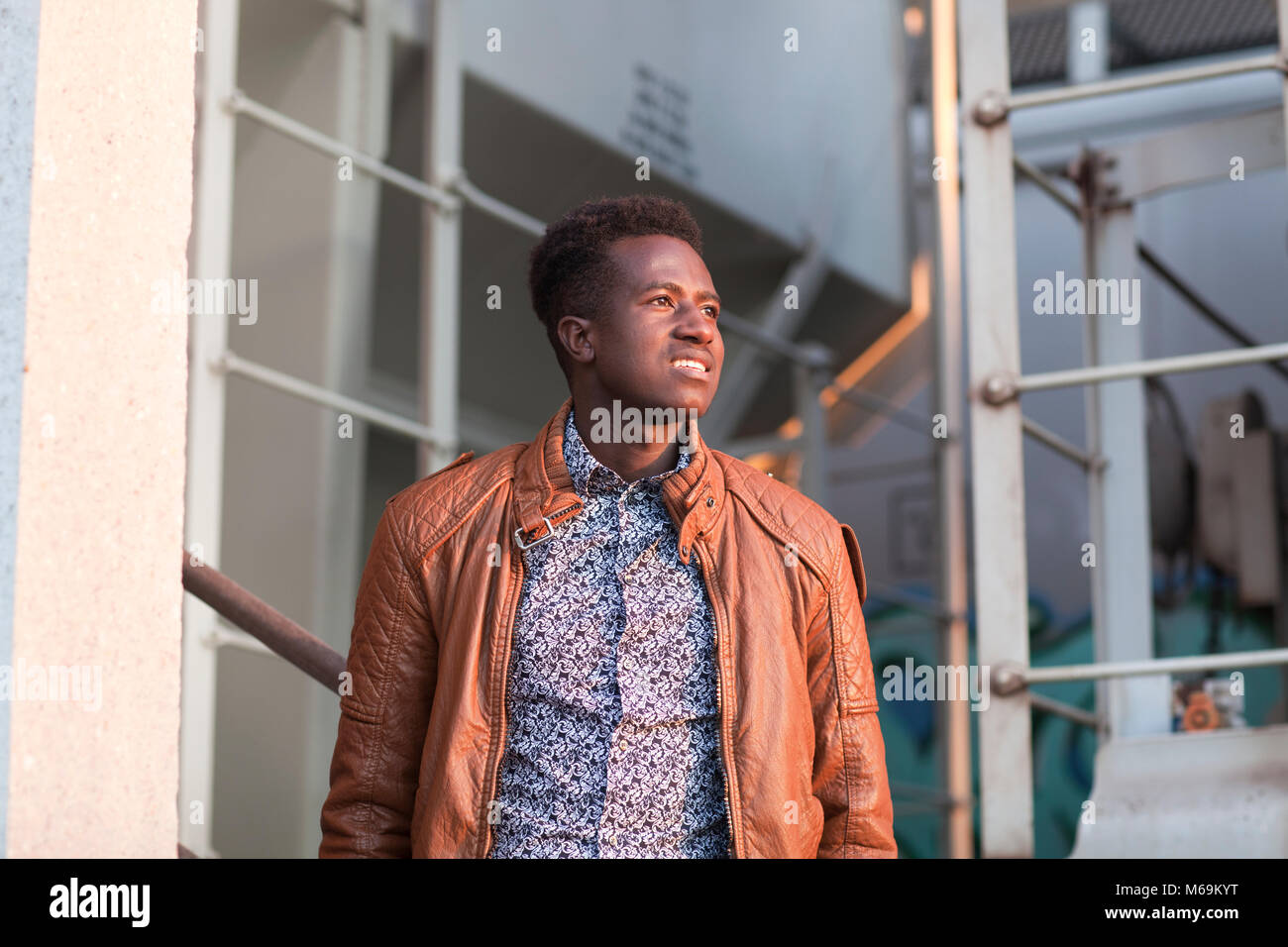 A handsome young black man in sunlight in an industrial setting Stock Photo