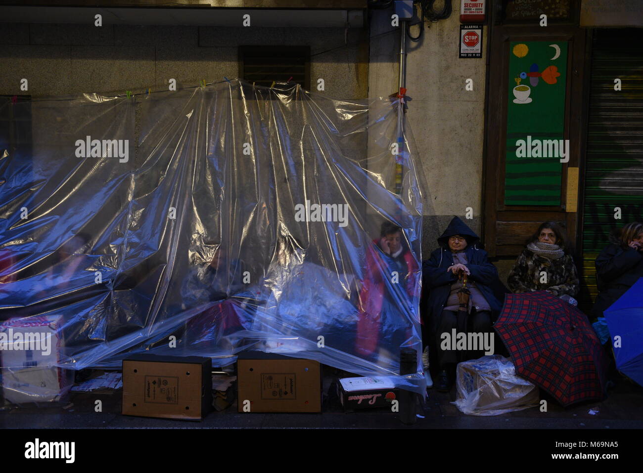 Madrid, Spain. 01st Mar, 2018. Catholic faithful protect themselves from the rain with a plastic as they wait in a street of Madrid to kiss the feet of a 17th Century wooden image of Christ, known as Cristo de Medinaceli. Credit: Jorge Sanz/Pacific Press/Alamy Live News Stock Photo