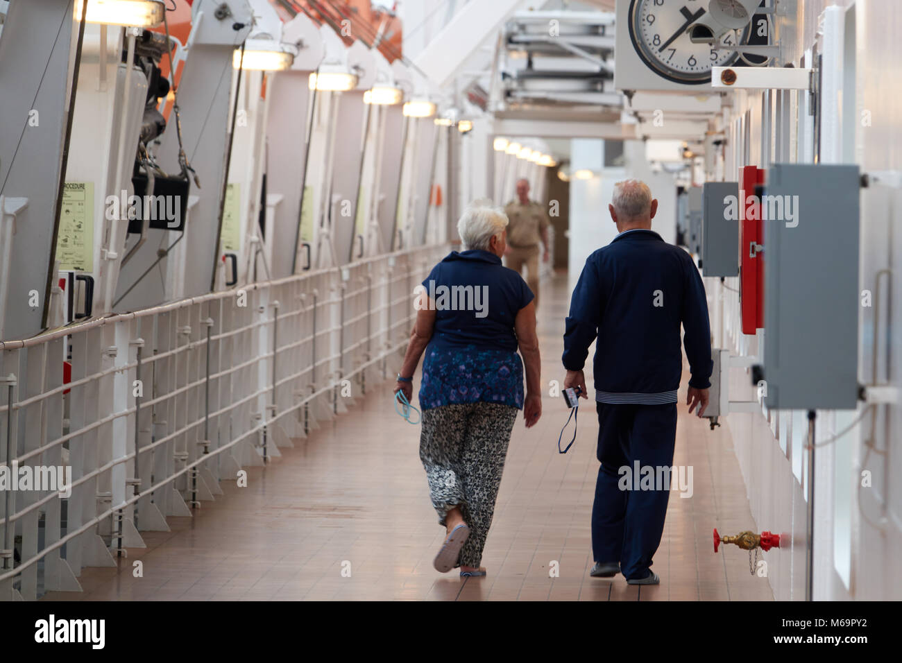 An elderly couple is walking along the deck of a cruise liner on a journey. Stock Photo
