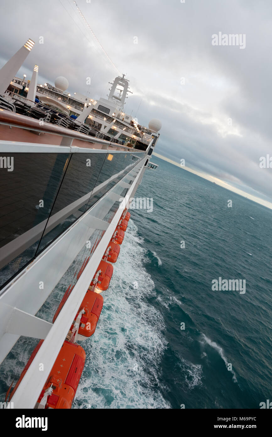 A sea cruise liner with lifeboats in the ocean in cloudy weather. Side view. Stock Photo