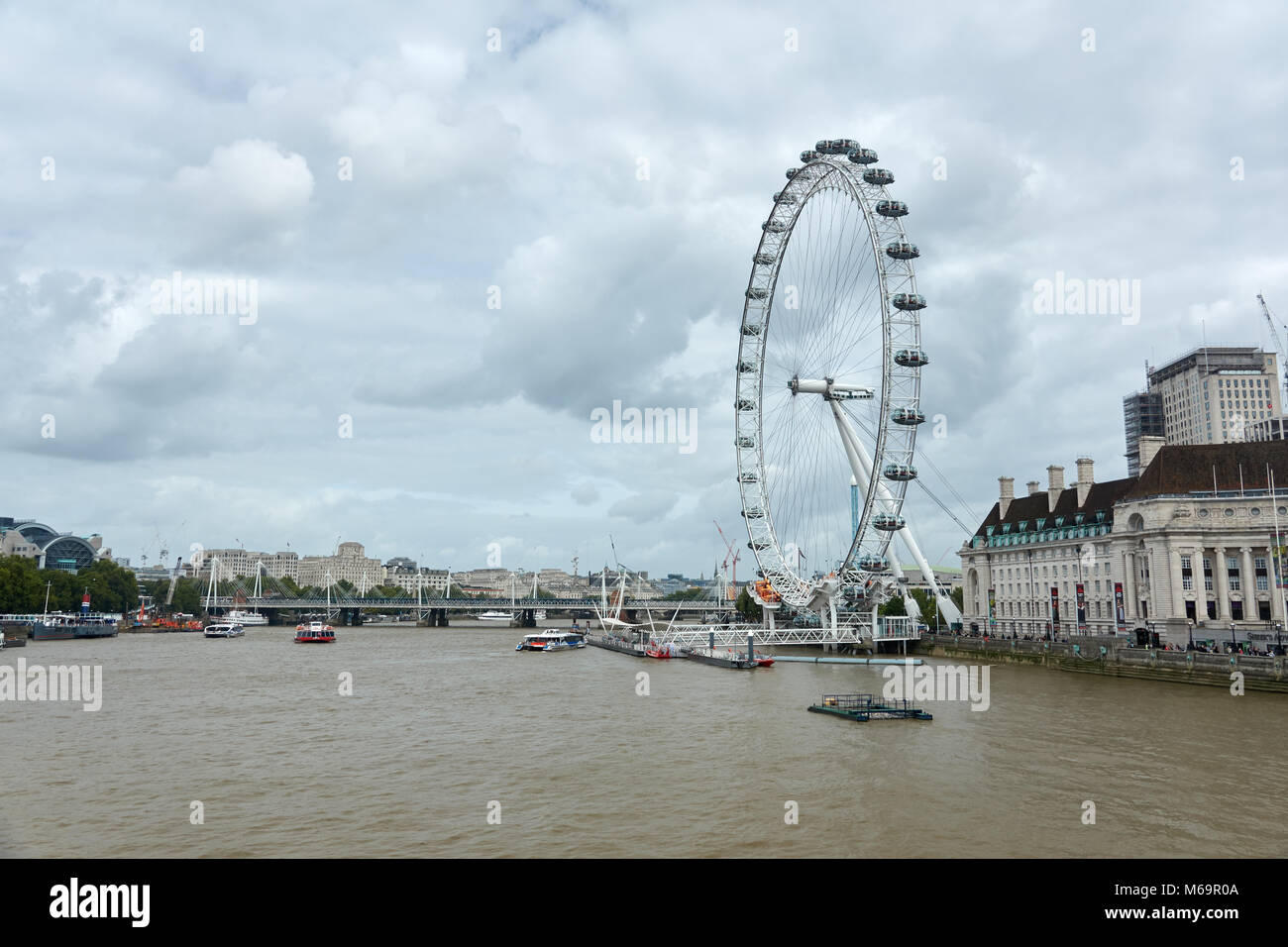 A large Ferris wheel. Sightseeing London's Eye. View from the bridge in cloudy weather. Stock Photo
