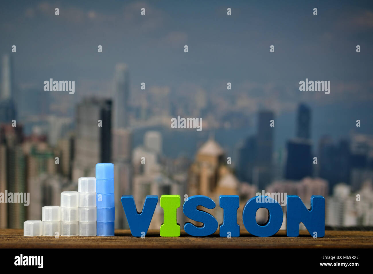 VISION text and graph on top wooden working table with city and office ...