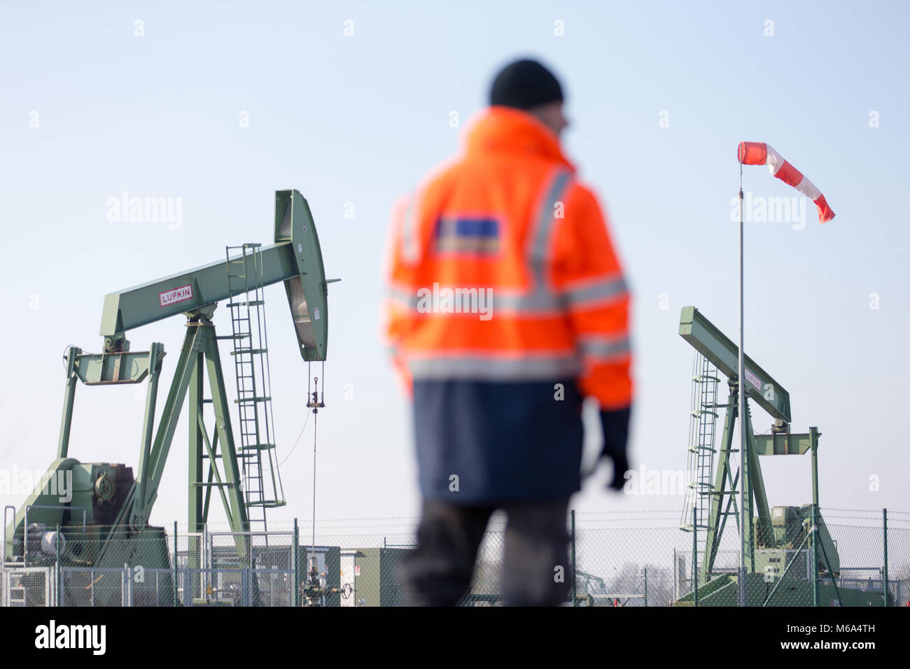 08 February 2018, Germany, Emlichheim: Geophysicist Tobias Fuhren stands in front of a horsehead pump. For more than 70 years oil production has been running in the county of Bentheim. Oil producer Wintershall is counting on seismic readings to detect undiscovered oil fields. Photo: Friso Gentsch/dpa Stock Photo