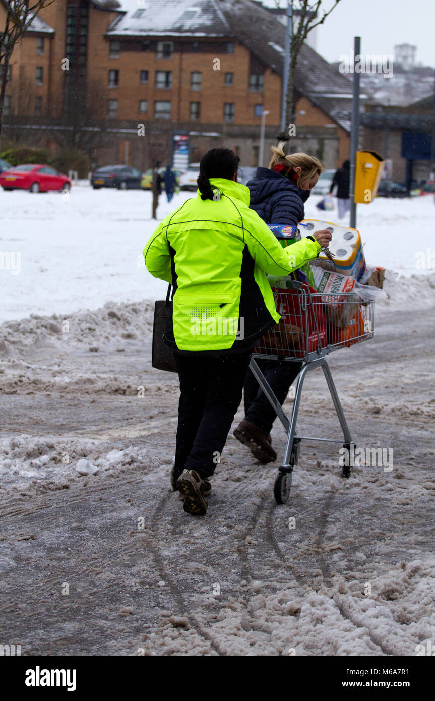 Dundee, Scotland, UK. 2nd March, 2018. UK Weather. The Siberian Beast from the East continues to cause disruption in the north east of Scotland with heavy snow falls and blustery cold winds. Shoppers struggling with their trolley full of messages in the slush and snow at the Lochee Stack Leisure Park in Dundee, UK. Credits: Dundee Photographics/Alamy Live News Stock Photo