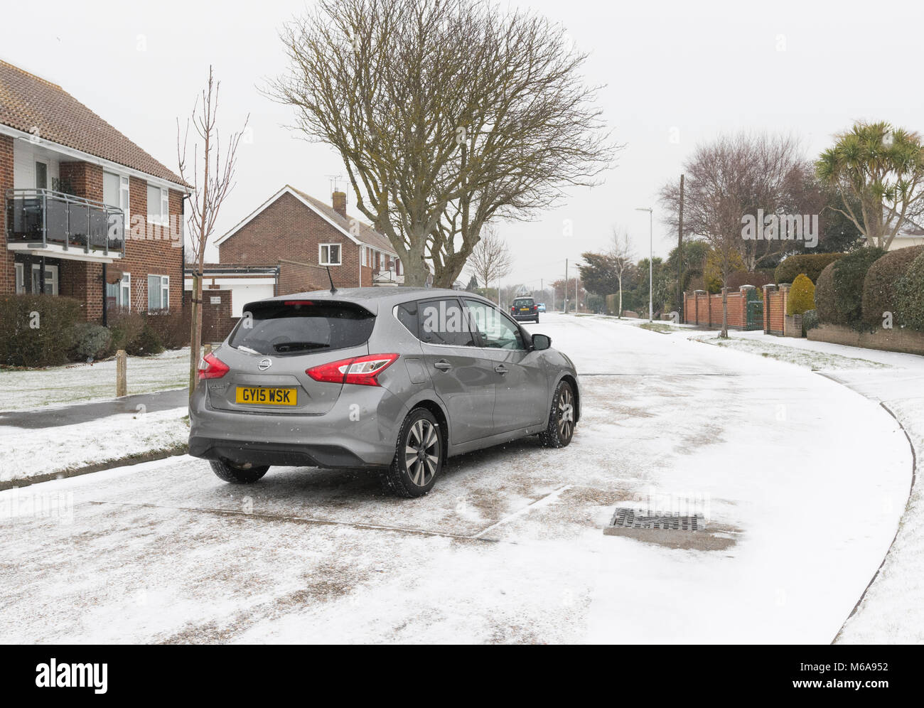 Car on a slippery snow covered road in Winter in England, UK. Dangerous driving conditions. Driving on an icy road. Stock Photo