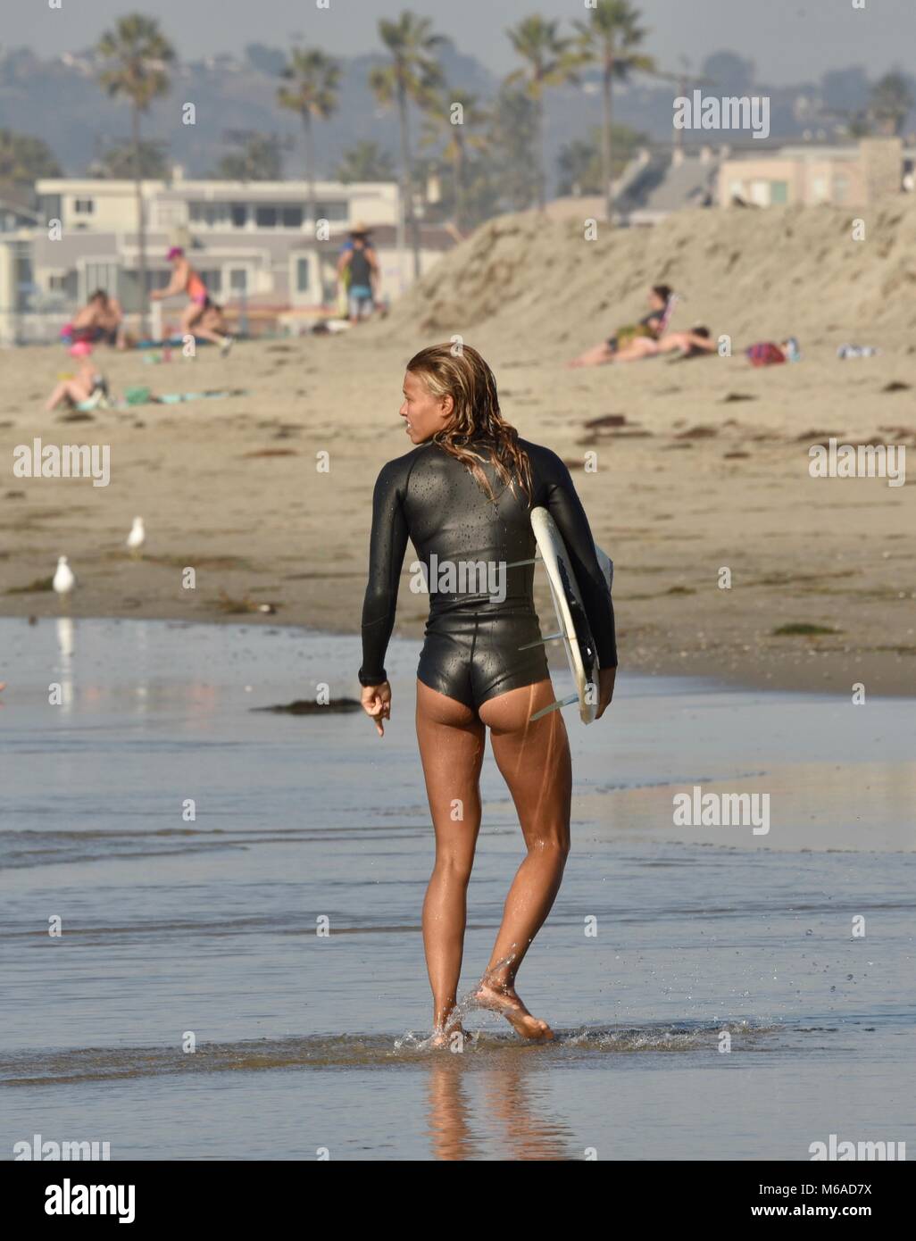 Beautiful and fit Latino woman surfer in wetsuit and with surfboard on