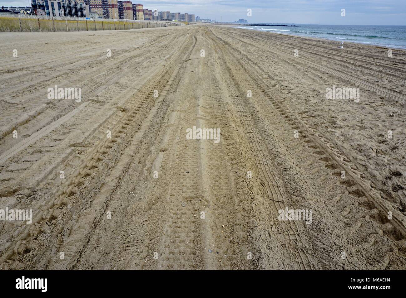 Tire tracks and footprints in the sand at Rockaway Park, Queens, New
