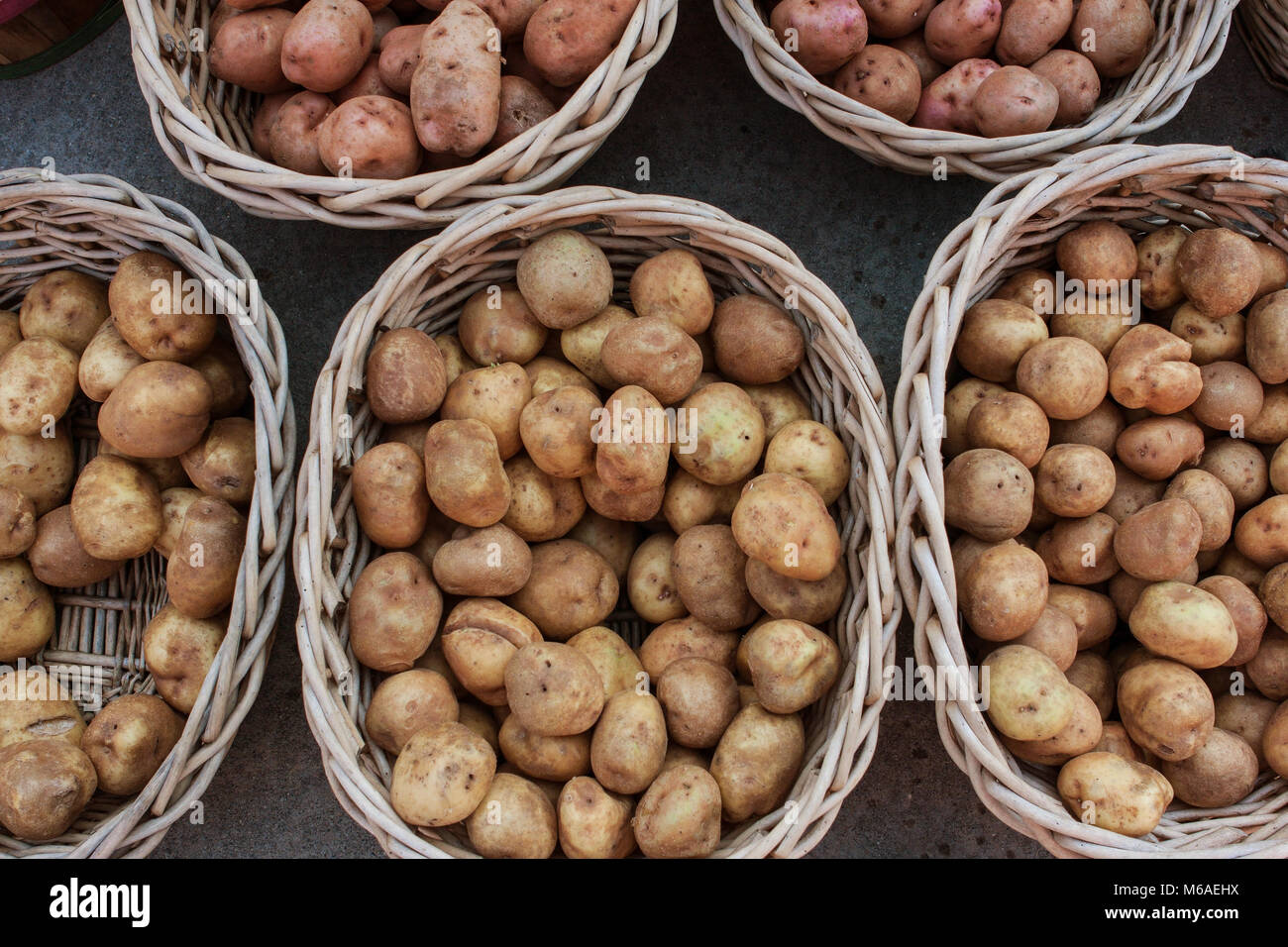 Potatoes sit in multiple wicker baskets at a local farmers market Stock