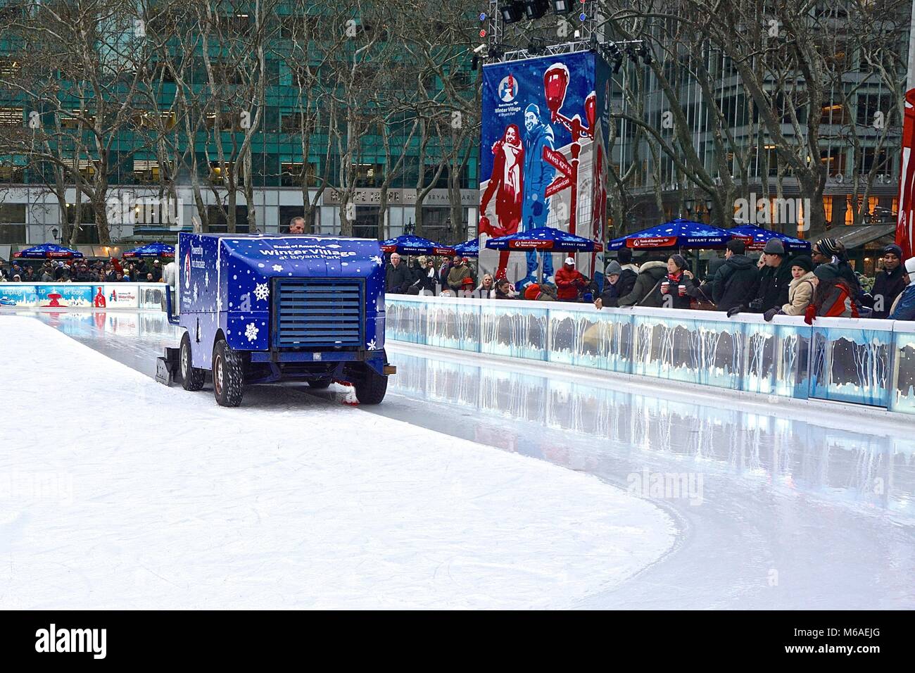 Holiday crowd enjoys snacks while man drives Zamboni machine to clean the ice at the Bryant Park Skating Rink, New York City. Stock Photo