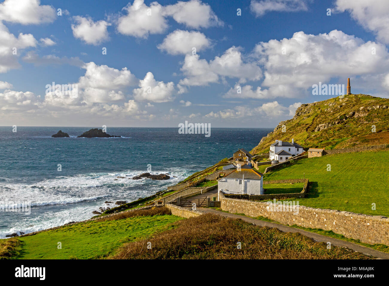 The chimney of a former tin mine now acts as a daymark for navigation around the coastline at Cape Cornwall and The Brisons rocks, England, UK Stock Photo