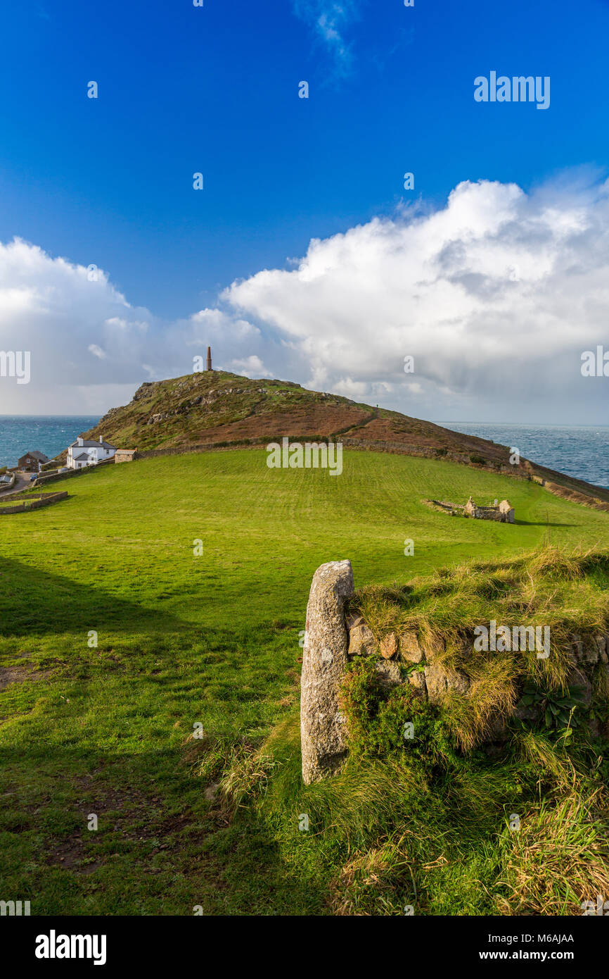 Granite gateposts and the ruins of St Helen's Oratory in a field, are overlooked by the chimney of a former tin mine at Cape Cornwall, England, UK Stock Photo