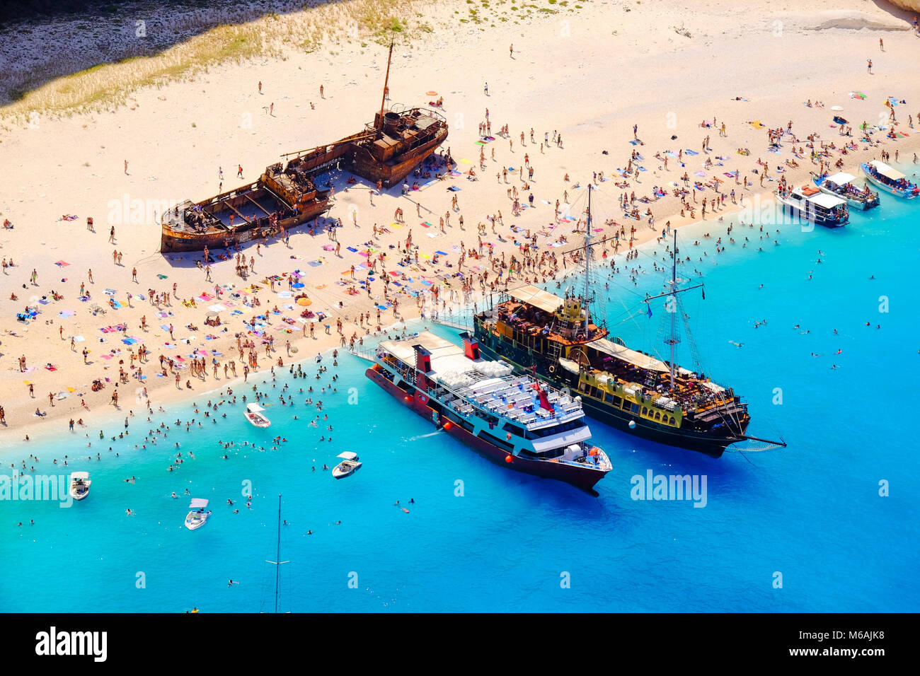 Boats anchored at Navagio beach, Zakynthos. Famous shipwreck on the beach and tourist bathing in the sun. Stock Photo