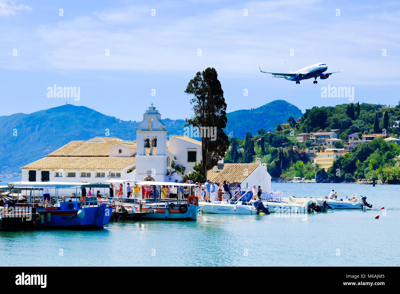 Tourists landing in Corfu Town, Greece. Pontikonisi island and monastery in front. Corfu island symbol and important tourist attraction. Stock Photo
