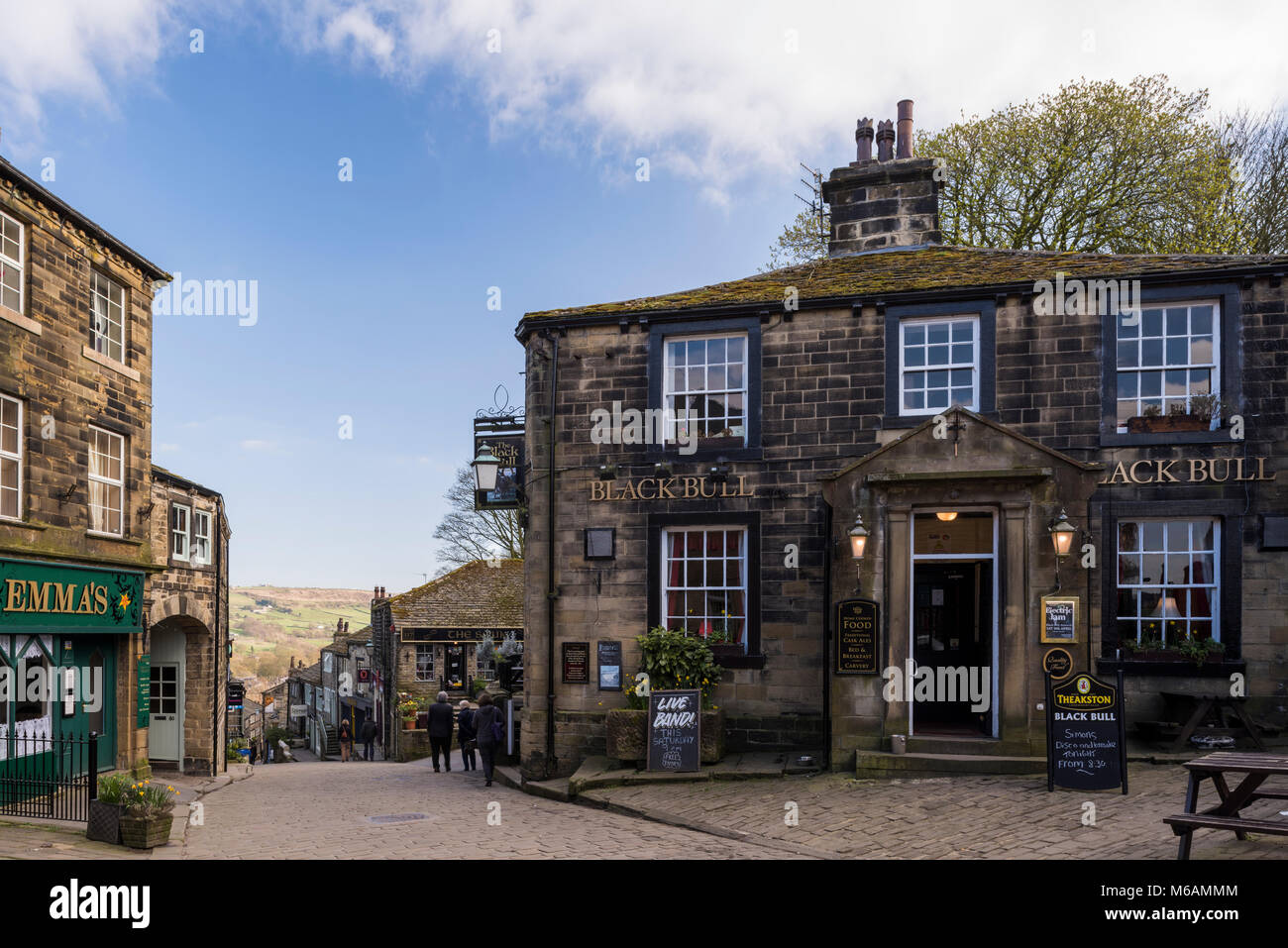 Haworth village where Bronte sisters lived, view down steep, quaint, narrow Main Street, Black Bull pub in foreground - West Yorkshire, England, UK. Stock Photo