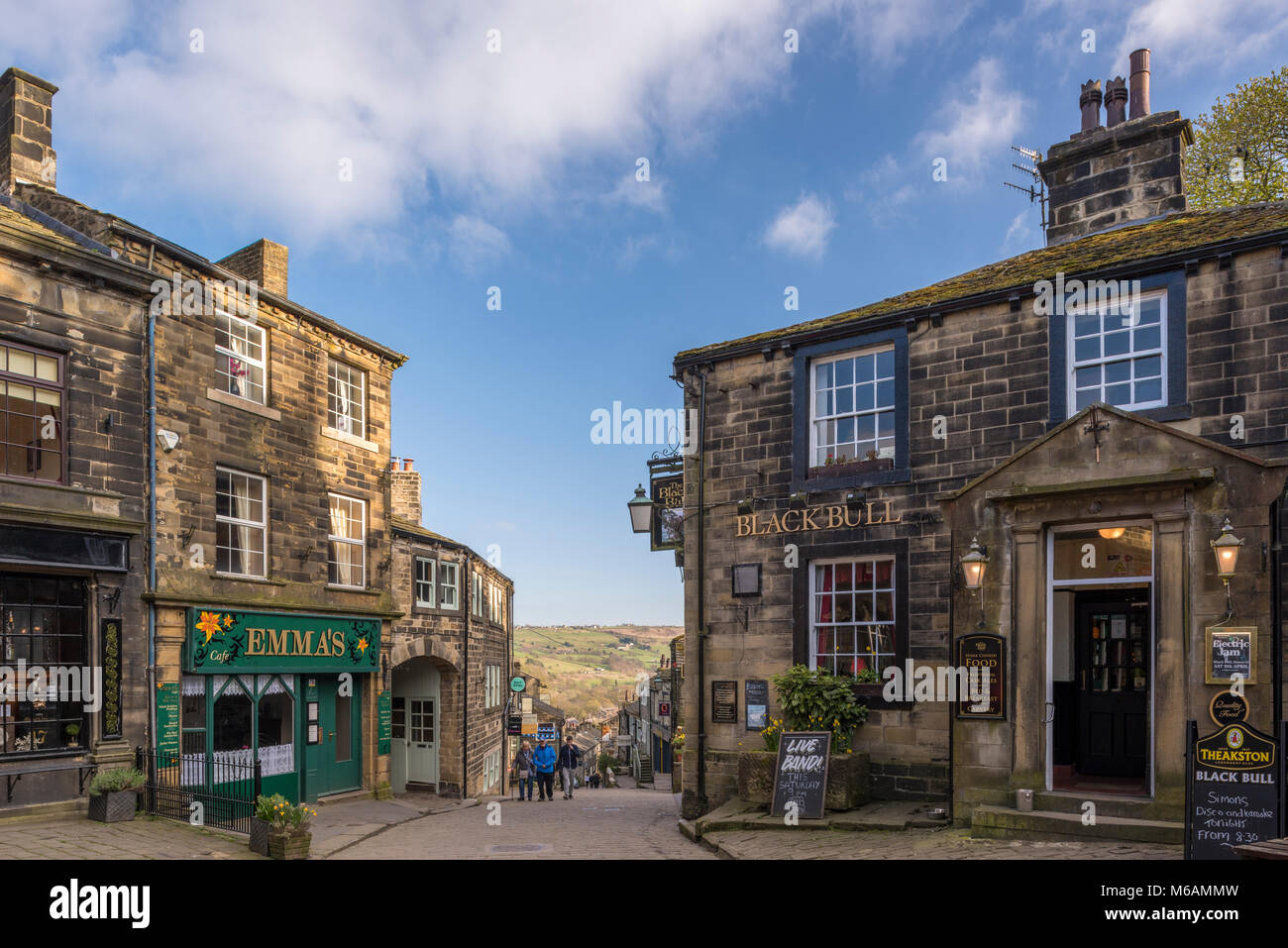 Haworth village where Bronte sisters lived, view down steep, quaint, narrow Main Street, Black Bull pub in foreground - West Yorkshire, England, UK. Stock Photo