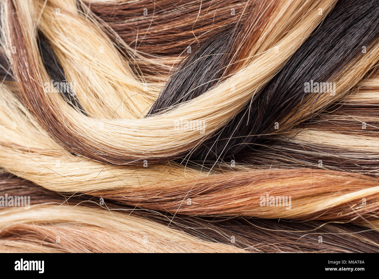 Real hair closeup. Hair texture pattern macro photo. Human european women's hair extension.. Black blonde brown. Stock Photo