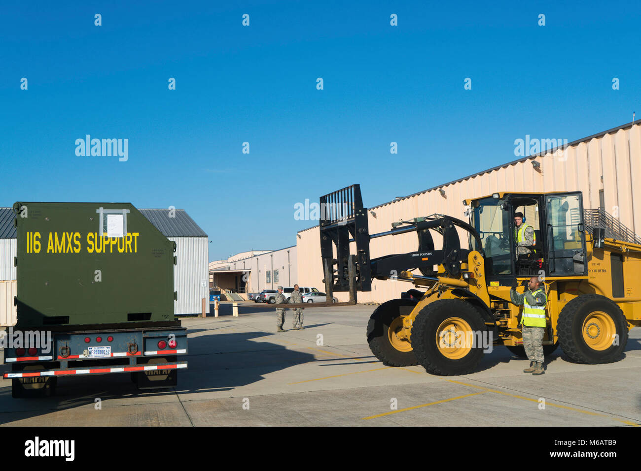 U.S. Air Force Senior Airman Brian Lacey, with the 78th Logistics Readiness Squadron (LRS), drives a forklift while transporting an Internal Airlift/Helicopter Slingable Container Unit from the 116th Aircraft Maintenance Squadron, to a simulated deployment line while Staff Sgt. Peter Scott, also with the 78th LRS, guides Lacey in place during Exercise Razor Blade 18-02 at Robins Air Force Base, Ga., Feb. 6, 2018. The exercise was a readiness assessment meant to evaluate and measure Team JSTARS ability to rapidly deploy and employ combat ready Airmen and airpower. The focus of the exercise revo Stock Photo