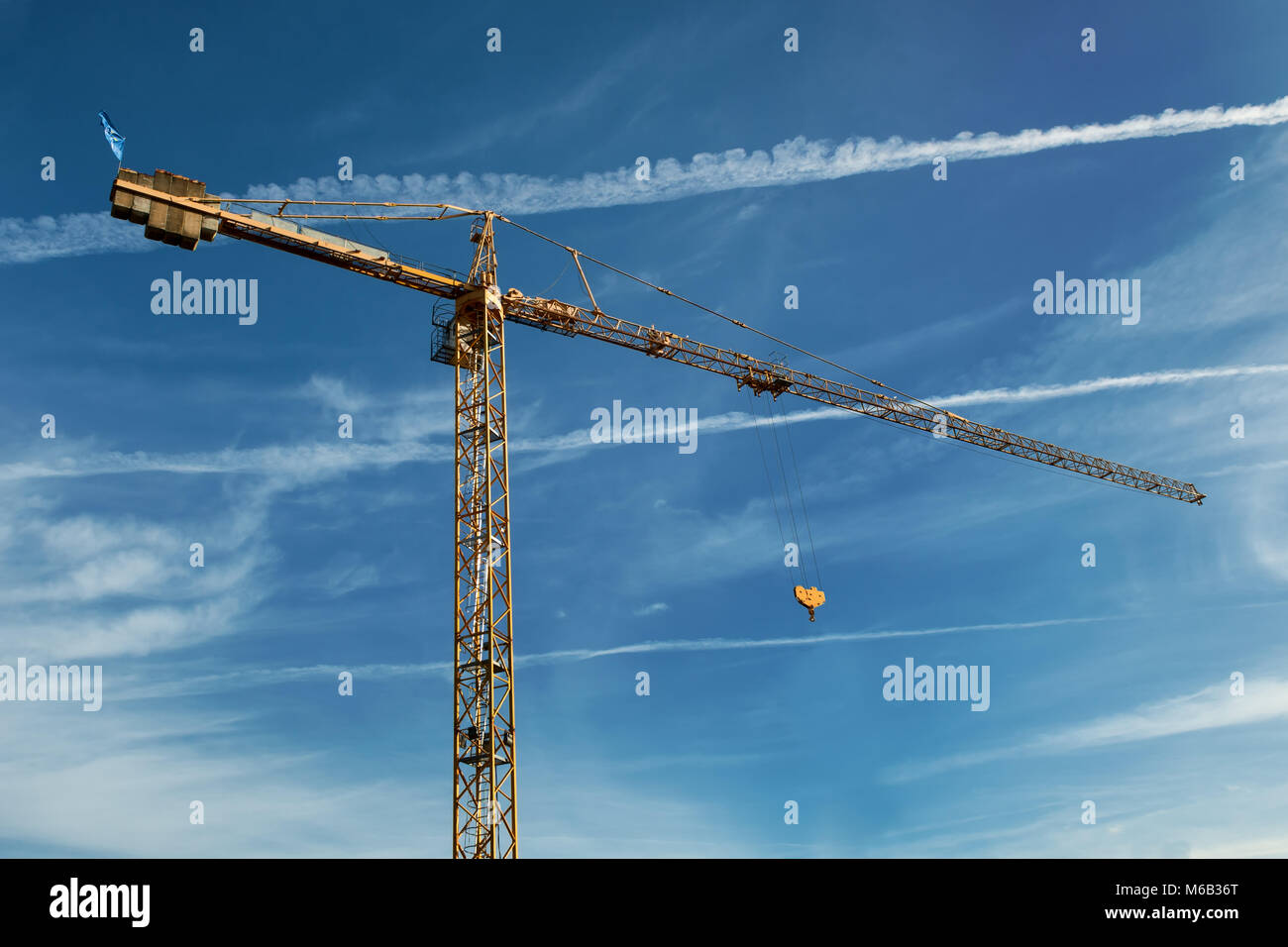 tall yellow working crane on blue cloudy sky background Stock Photo - Alamy