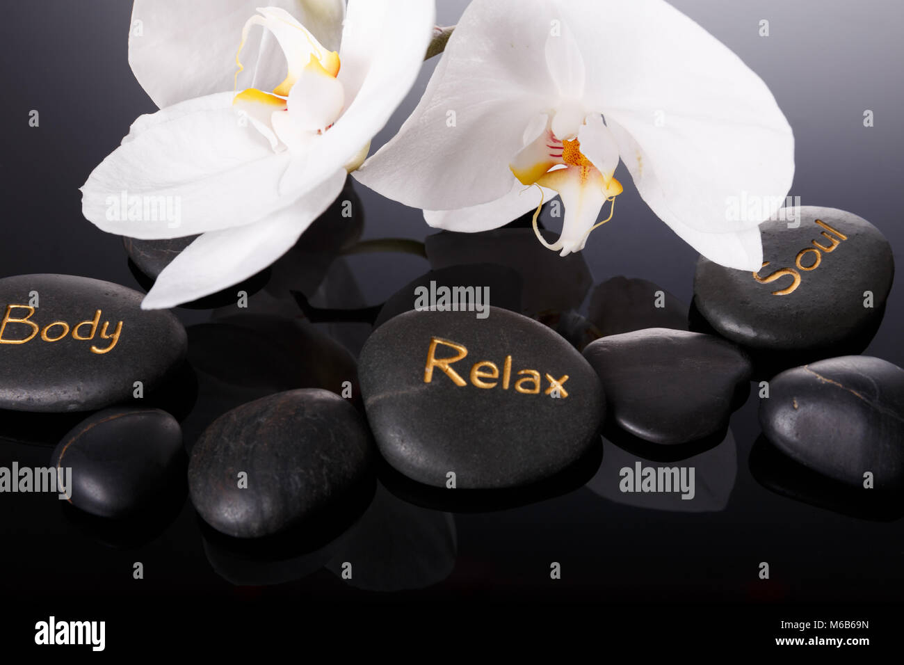 Spa concept, white orchid, black therapy stones with the inscription ...