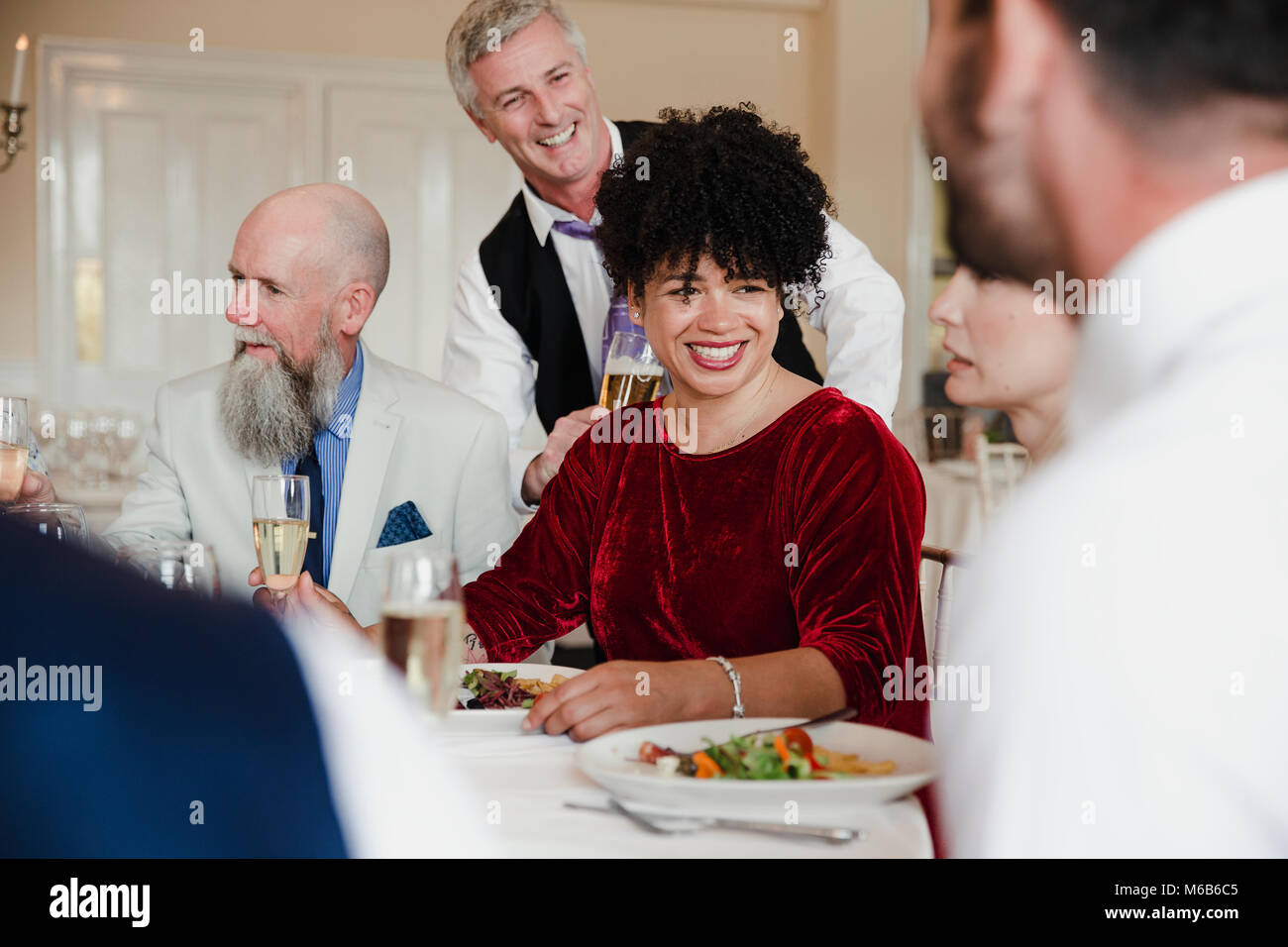 Wedding guests are socialising while enjoying the starter of their meal ...