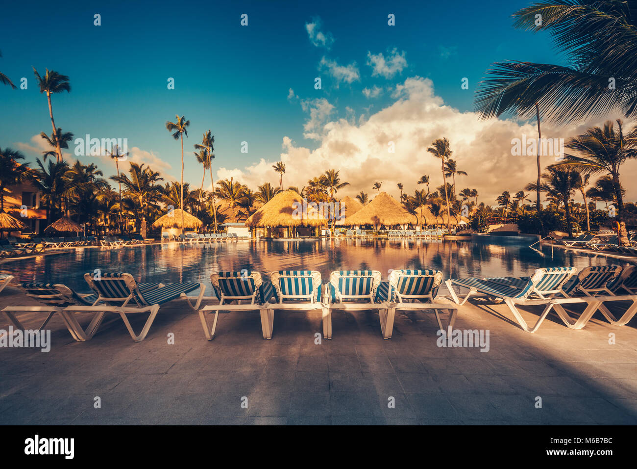Tropical swimming pool and palm trees in luxury resort Stock Photo - Alamy