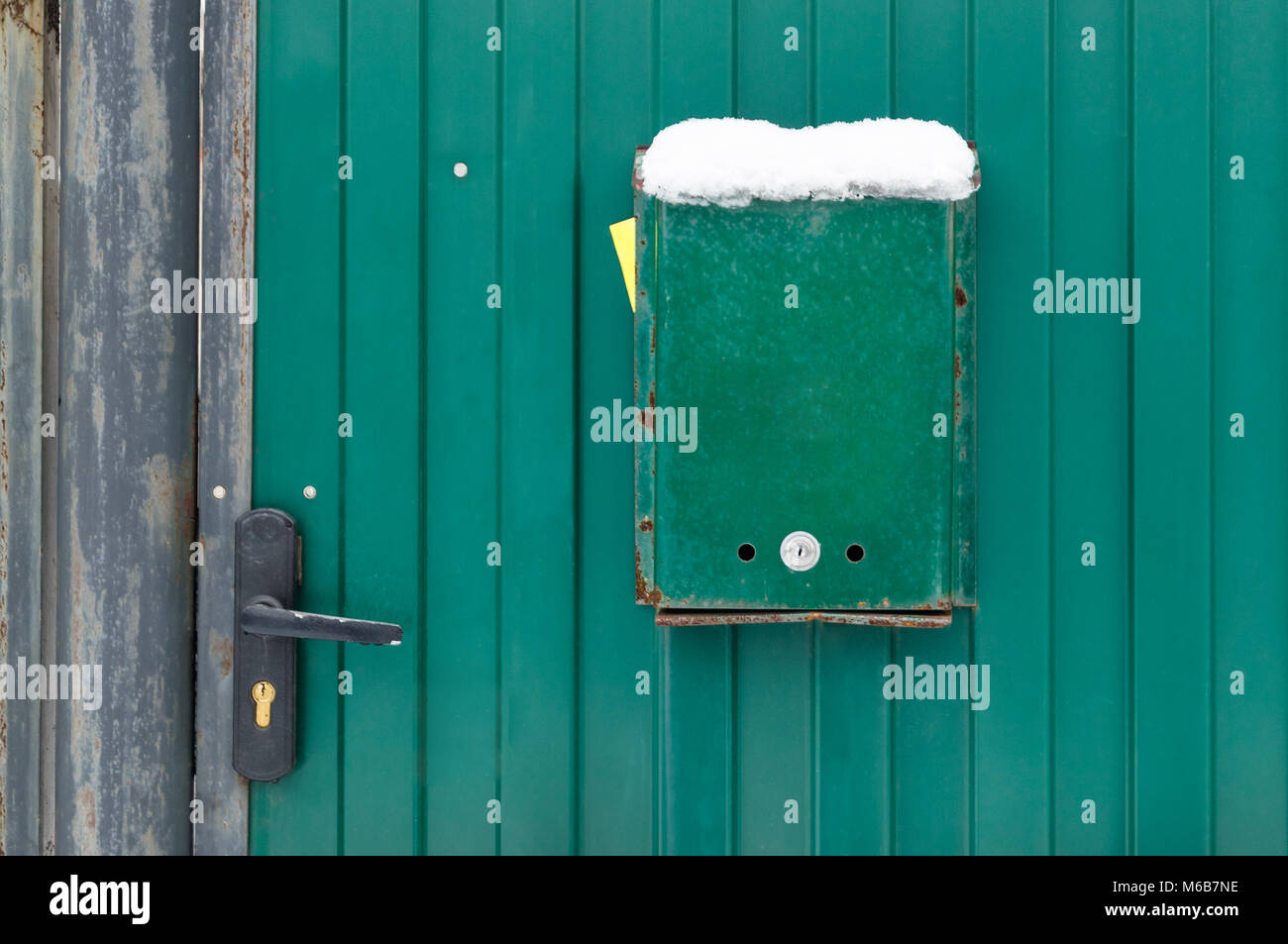 The mailbox is green on the metal gate of the house with a lock and a handle. Green background Stock Photo