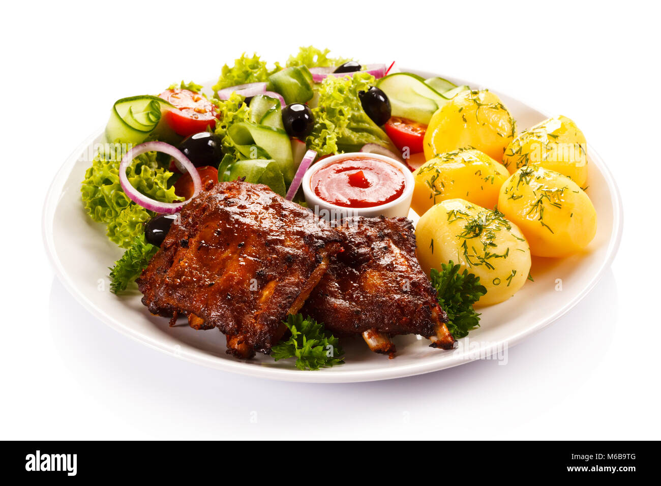 Grilled ribs, French fries and vegetables on white background Stock Photo
