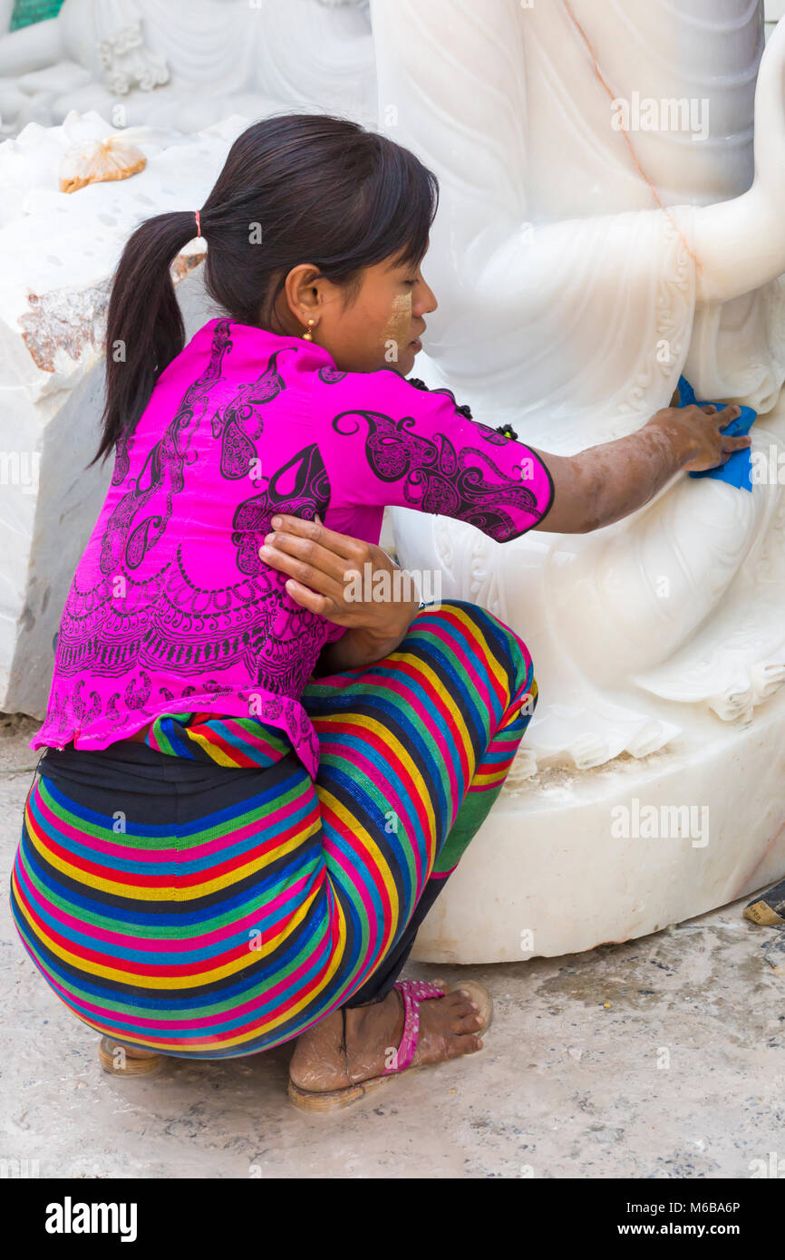 Young woman rubbing down marble Buddha, Amarapura, Mandalay, Myanmar (Burma), Asia in February - working at marble stone carving workshops in dust Stock Photo