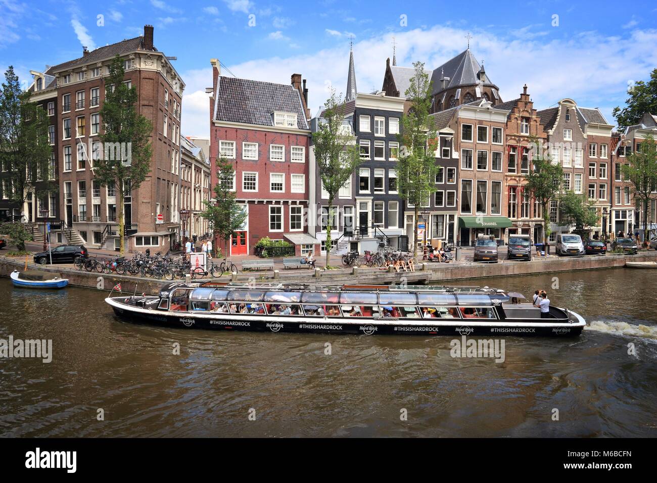 AMSTERDAM, NETHERLANDS - JULY 10, 2017: People visit Herengracht canal in Amsterdam, Netherlands. Amsterdam is the capital city of The Netherlands. Stock Photo