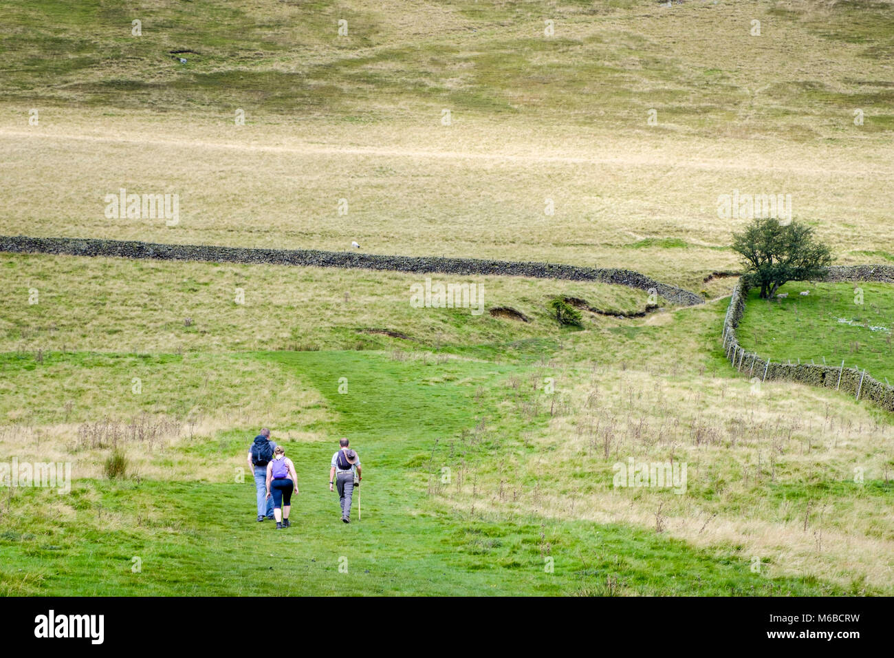 Hikers in the countryside with a large hill ahead of them. Vale of Edale, Derbyshire, Peak District, England, UK Stock Photo