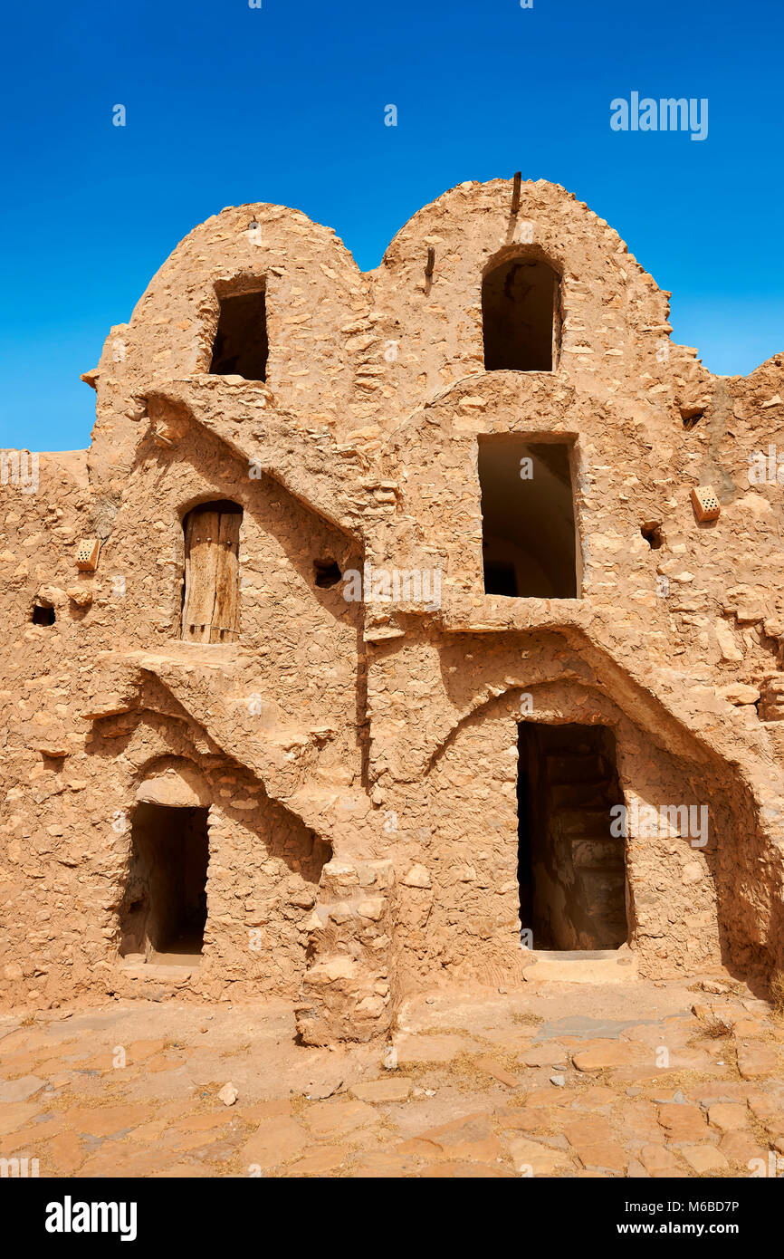 The northern Sahara ghorfa storage graneries of the traditional Berber mud brick fortified Ksar of Hedada or Hadada, near Tetouin, Tunisia, the settin Stock Photo
