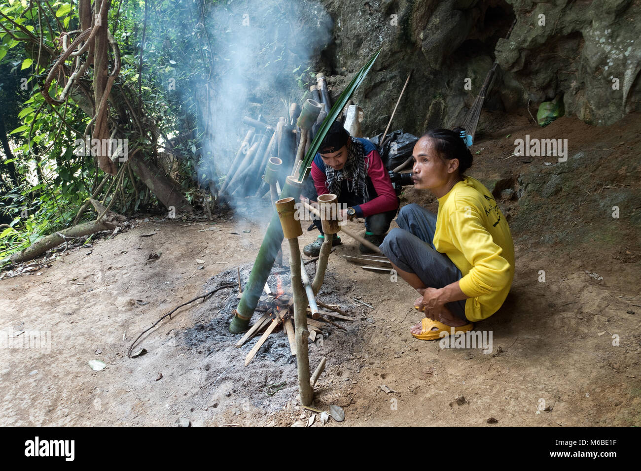 Thai man boils water in an old fashioned way, wood fire with water in a ...