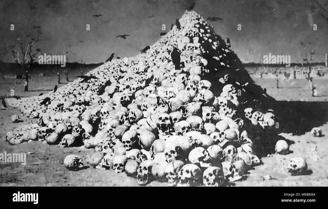 FUTILITY OF WAR - A gruesome pile of human skulls  being picked over by crows (from an old Russian postcard) Stock Photo