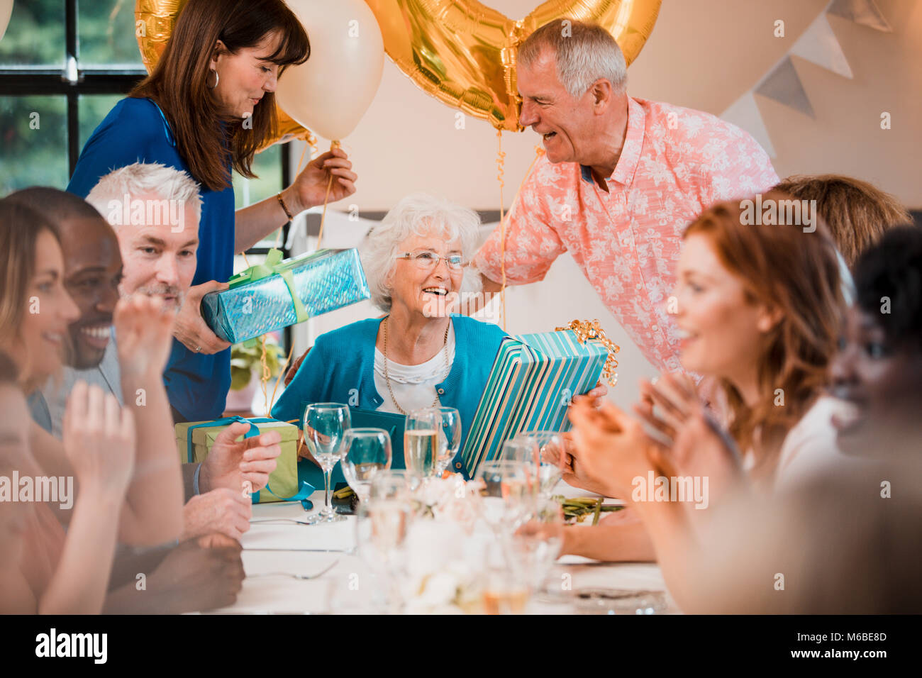 Senior woman is overwhelmed with emotion as she is surprised with a birthday party by her friends and family. Stock Photo