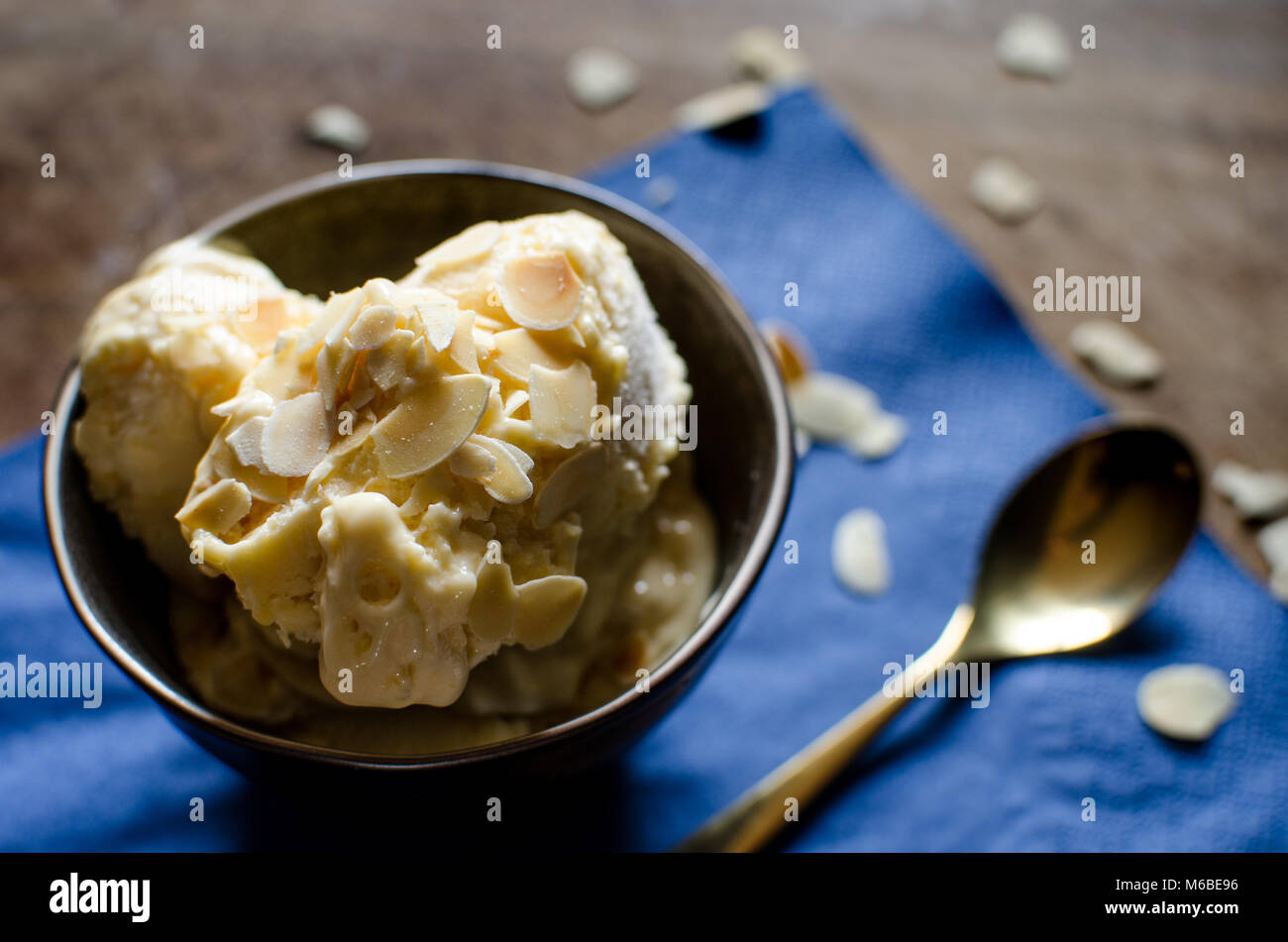 Passion fruit Semifreddo with almonds on a dark background on a wooden board and a dark blue paper napkin Stock Photo