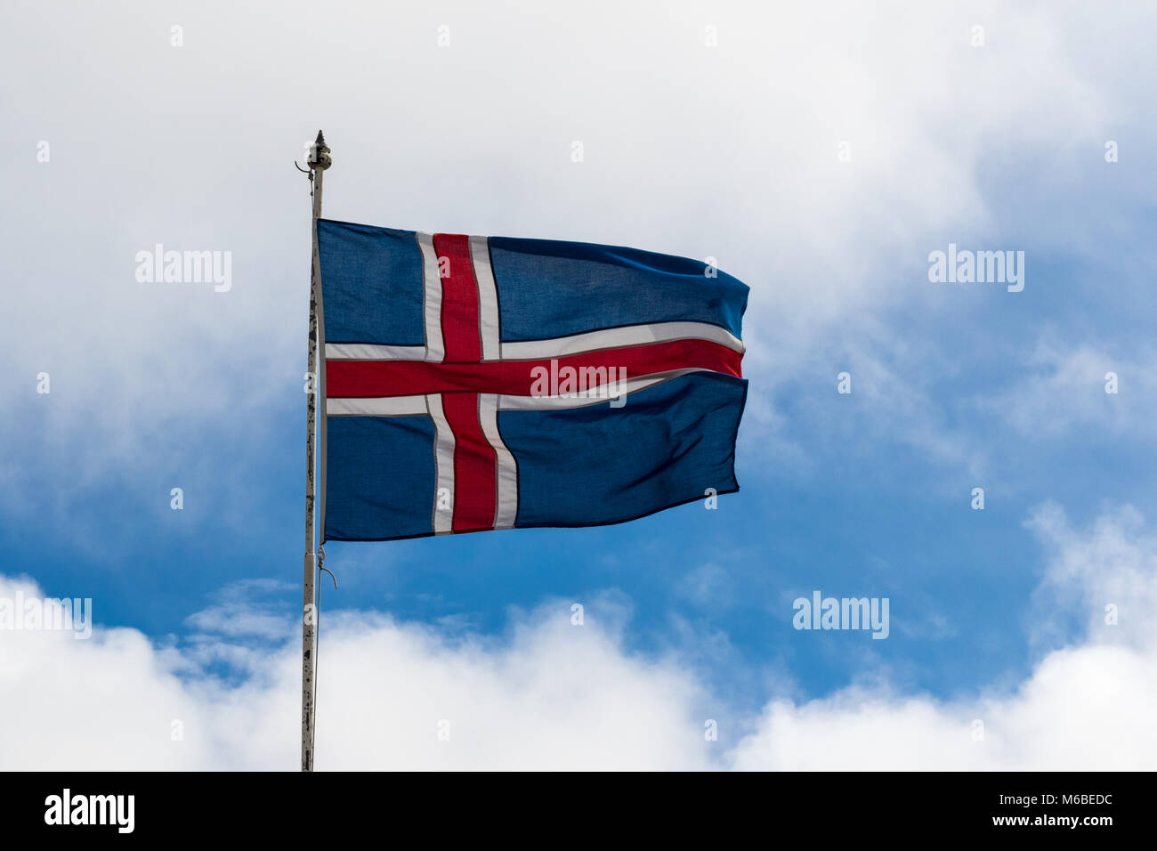 Icelandic Flag blowing in the sunshine against a blue sky with dappled cloud Stock Photo