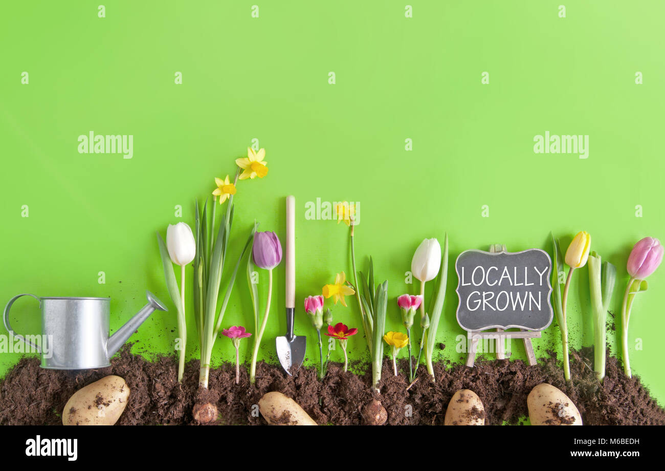Locally grown message on a chalkboard on top of a flower bed, with