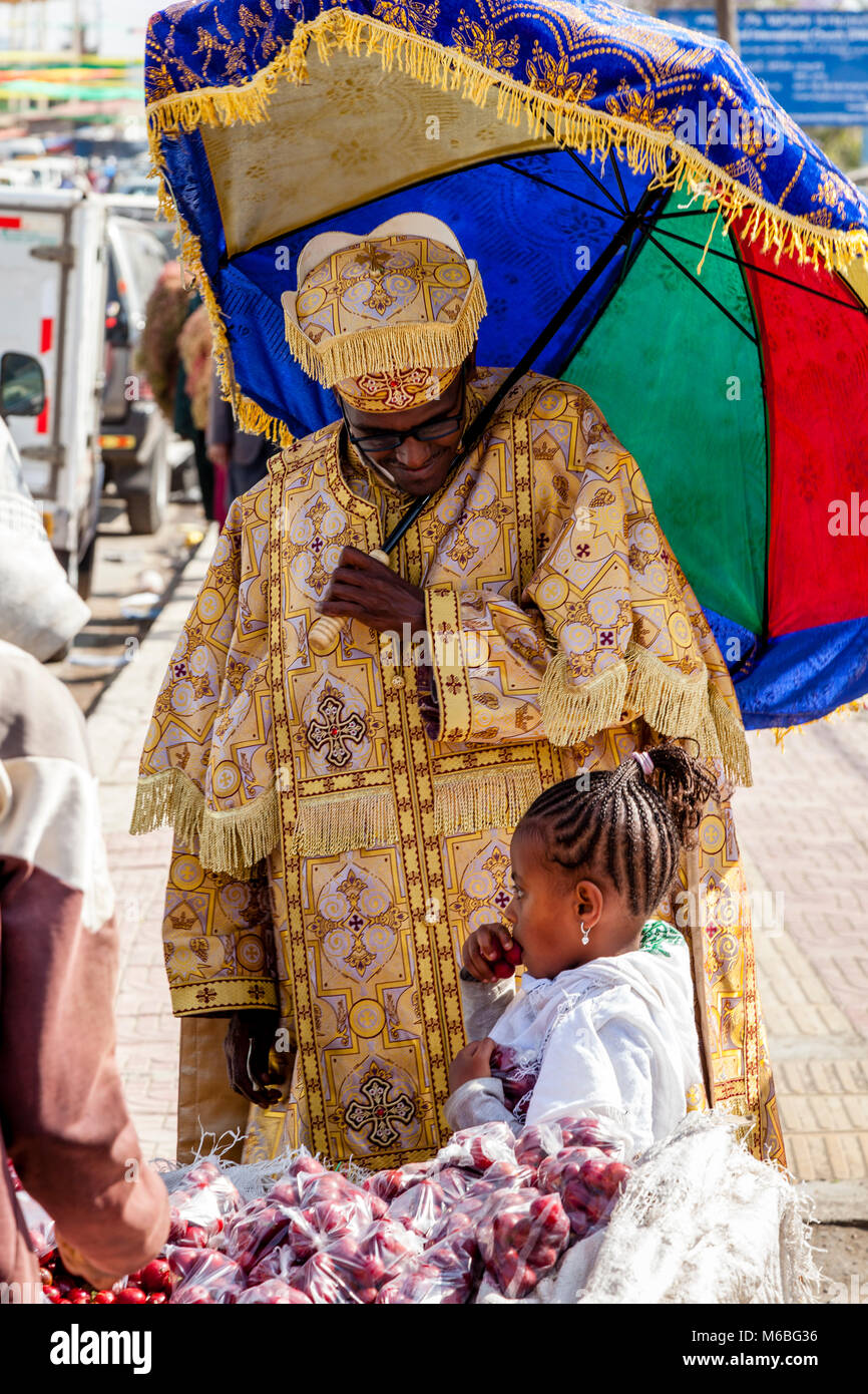A Christian Orthodox Priest Buys Fruit For A Child During Timkat (Epiphany) Celebrations, Addis Ababa, Ethiopia Stock Photo