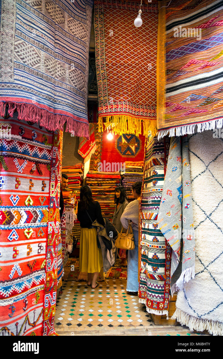 People shopping for Moroccan rugs inside a stall in the souq, Fes, Morocco Stock Photo