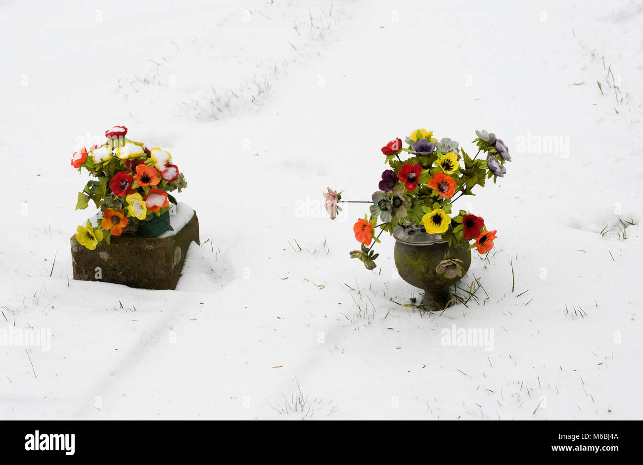 Silk flowers on graves in winter. Stock Photo