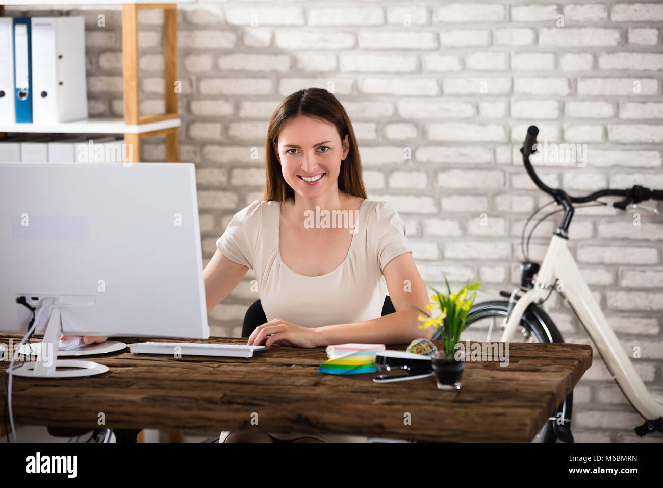 Smiling Young Woman Using Computer In Office Stock Photo - Alamy