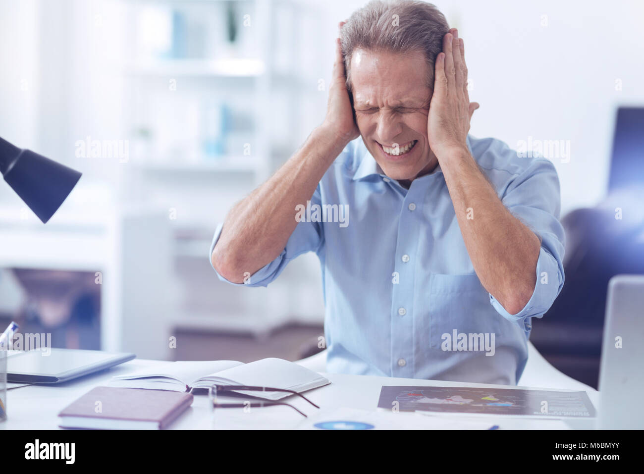 Unhappy stressed out man covering his ears Stock Photo