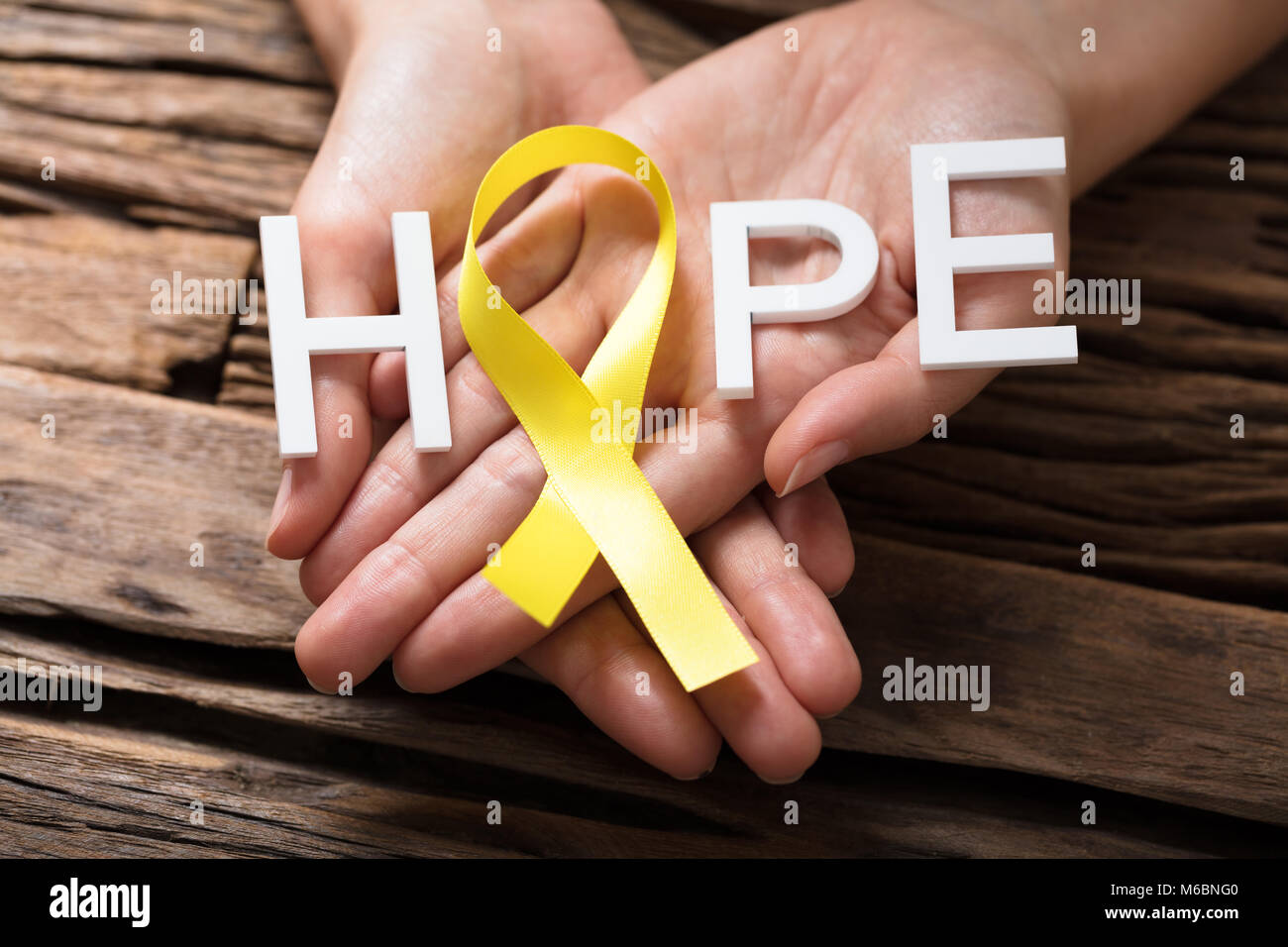 Person's Hand Showing Ribbon With Hope Text To Support Childhood And Bladder Cancer Stock Photo
