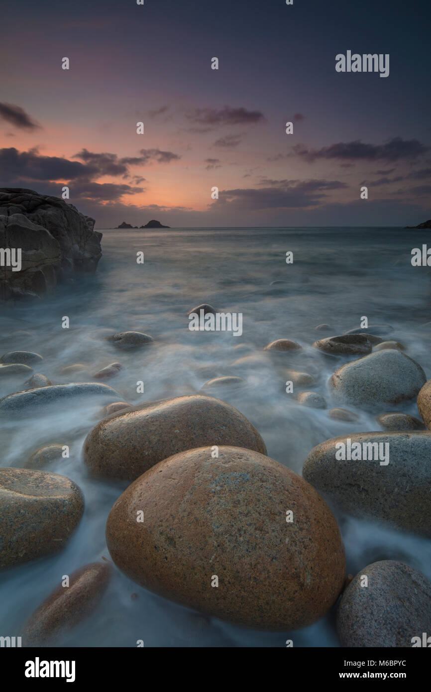 Boulders on Porth Nanven beach looking towards the Brisons at sunset Cot Valley near St Just Cornwall Stock Photo