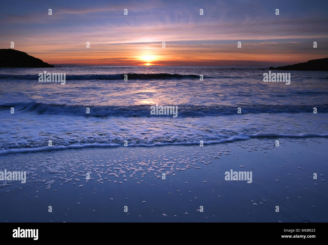 A view of Clachtoll Bay, looking across the Atlantic Ocean, as the sun sets. Stock Photo