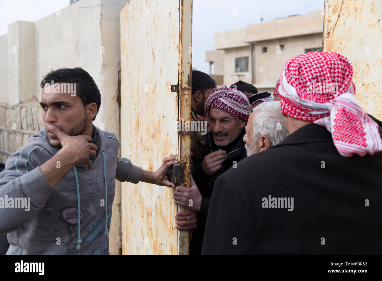 Mosul, Iraq. 8th December 2016 - Mosul locals try to convince their way into a barricaded school to seek shelter as fighting continues in the city of M Stock Photo